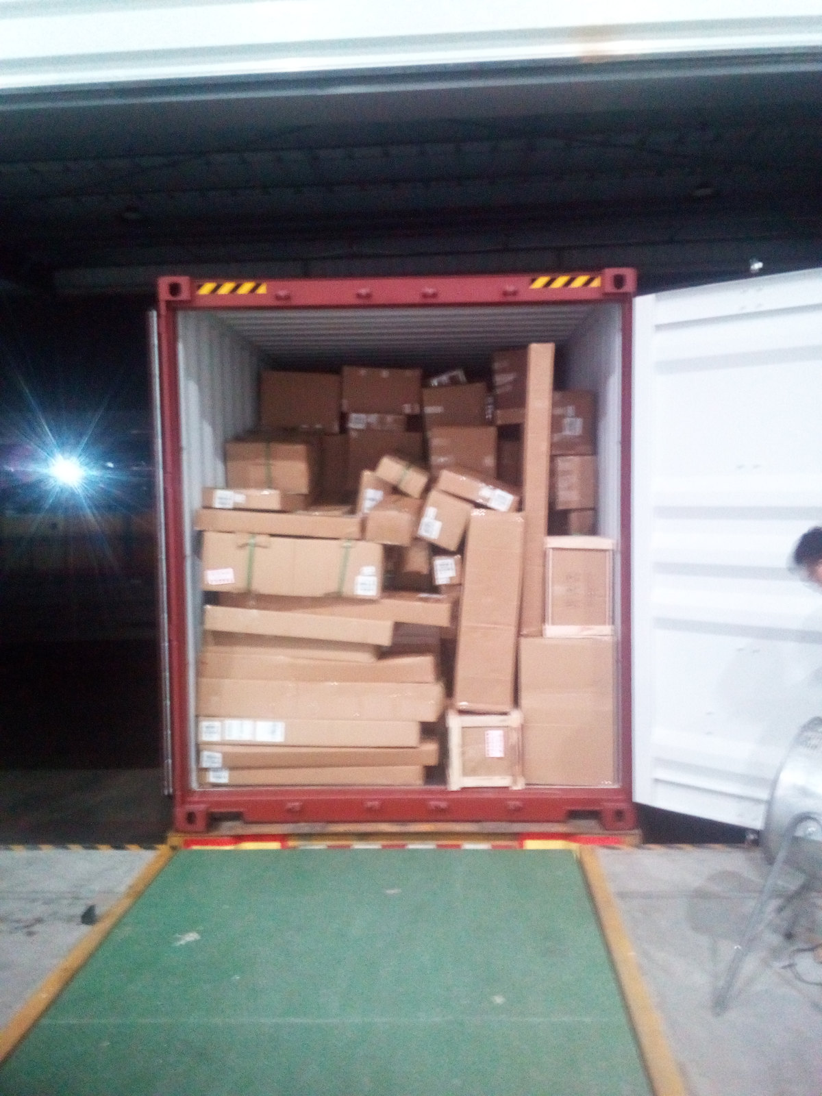 Container doors open at night during loading, with the interior packed with cartons